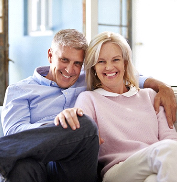 older couple sitting in couch and smiling with All-on-4 in Braintree 