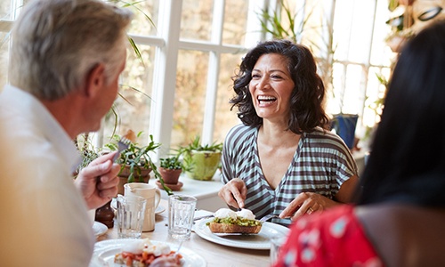Woman smiling while eating meal with friends at restaurant