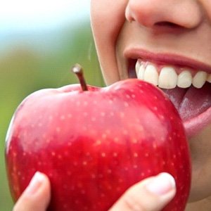 close up person eating a red apple