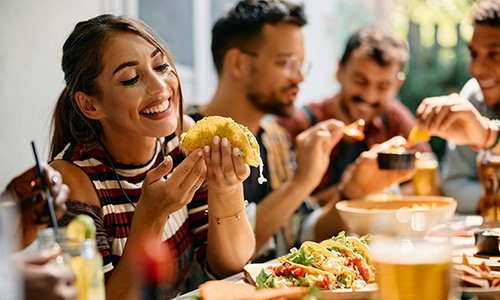 Woman smiling while eating lunch with friends at restaurant