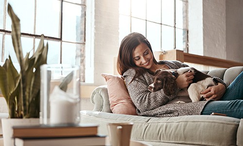 Woman smiling while relaxing on couch with dog