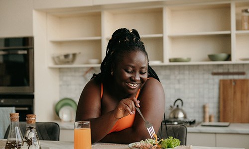 Woman smiling while eating healthy meal at home