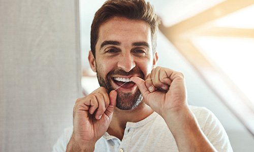 Man smiling while flossing his teeth