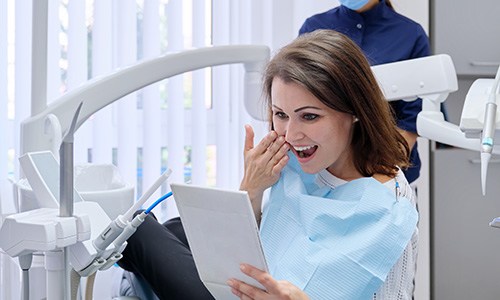 Woman smiling at reflection in handheld mirror