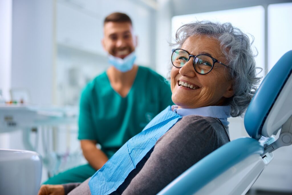 Smiling woman sitting in treatment chair next to dentist